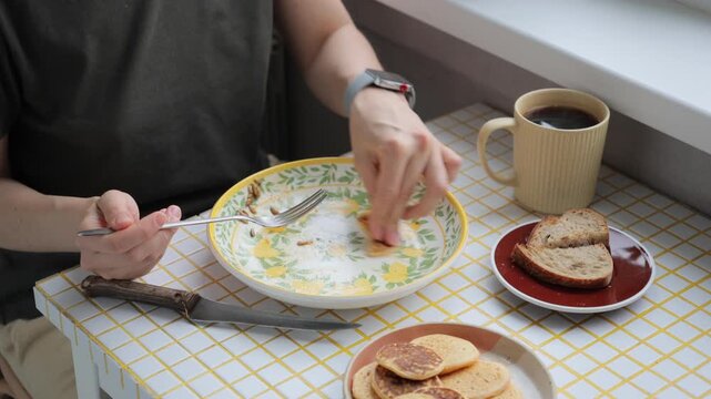 person finishes their breakfast or lunch in kitchen. delicious and healthy food cooked at home. woman eats flatbread pancakes and drinks coffee. vegetarian diet for body health. high quality 4k video
