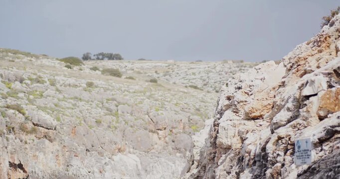 Split Focus View of Rugged Rocky Cliff with Sparse Vegetation and Hazy Landscape Background