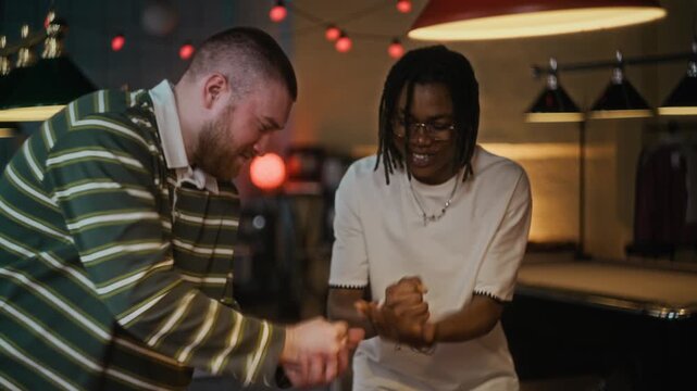Tilt up shot of young adult African American man playing rock paper scissors with Caucasian best friend while deciding on who taking break shot in billiards game at pool hall
