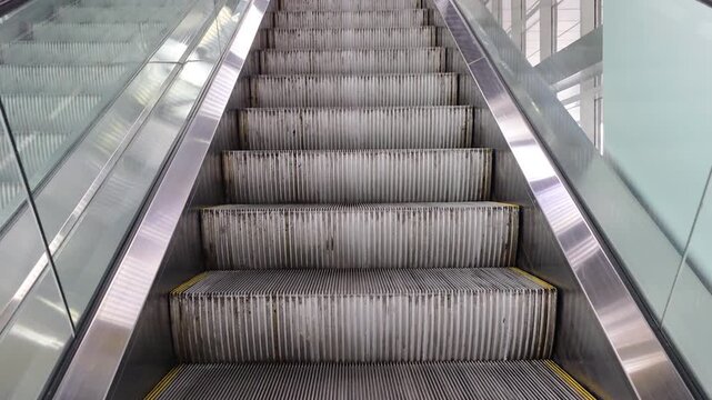 Escalator moving featuring textured metal steps and yellow warning lines, highlighting elements of urban travel, modern architecture, and public transportation infrastructure