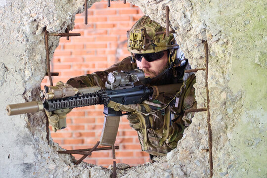 Tactical Soldier Aiming Assault Rifle Through Broken Concrete Wall During Urban Combat Training Mission