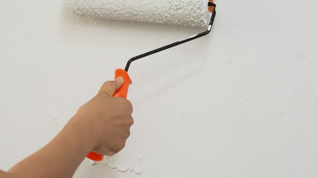 Roller Brush Painting, Worker painting on surface wall Painting apartment, renovating with white color paint. Leave empty copy space to write descriptive text beside.