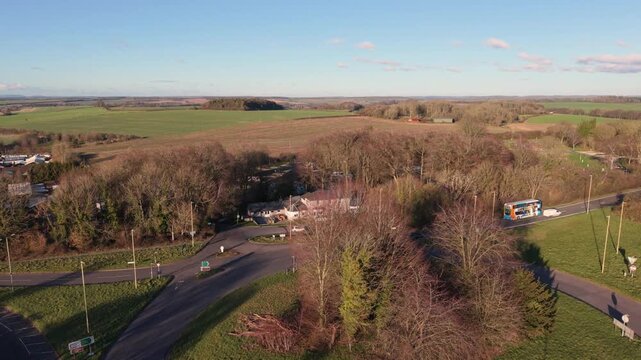 596
Forward flight over Percy Hobbs roundabout Alresford Road Winchester Hampshire with views across extensive rolling countryside in Southdowns National Park in late afternoon sun with blue sky