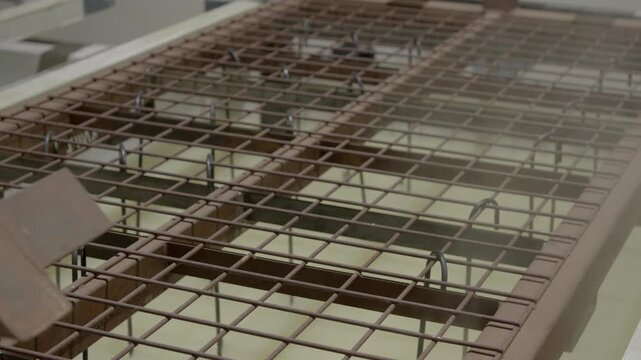 Metal sheets are fully submerged in a coating bath during the KTL coating (cathodic dip coating) process in an industrial facility. The components remain immersed while electrochemical deposition form