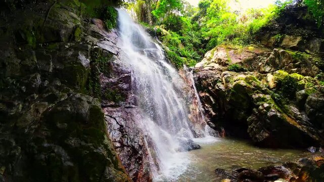 Slow motion static shot of Marinka Waterfalls in Minca, Colombia. Serene cascading water falling into a jungle pool surrounded by lush tropical greenery. Peaceful nature and wellness background.