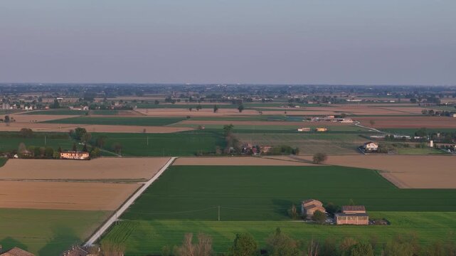 Agricultural landscape in Pianura Padana near Piacenza Emilia Romagna Italy with patchwork fields, scattered farm buildings and rural roads across flat alluvial plain, drone pullback shot
