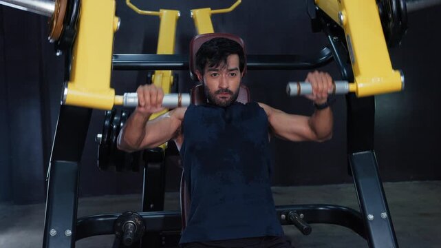 Man Performing Upper Body Machine Exercise in Gym. Male Fitness Using Shoulder Press Equipment for Strength Workout, upper body development and Training athletic effort, and a focused gym routine.