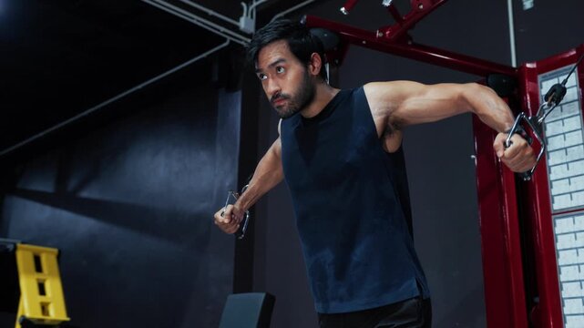 Focused Male Athlete Performing Standing Cable Fly for Muscle Training in Gym. Man Working Out with Cable Machine During Chest Strength Session in Fitness.