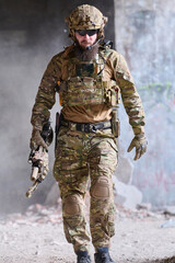 Obraz premium Bearded Soldier in Tactical Camo Gear Walking Through Urban Ruins With Helmet and Rifle