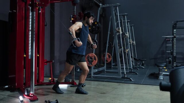 Athletic Male Exercising with Cable Station During Chest Training, strength development and upper body exercise in Gym. Athlete Performing Controlled Cable Fly Motion During upper body training.