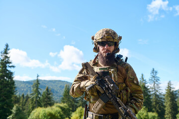 Obraz premium Bearded Soldier in Tactical Gear Holding Rifle in Forest During Military Training Exercise