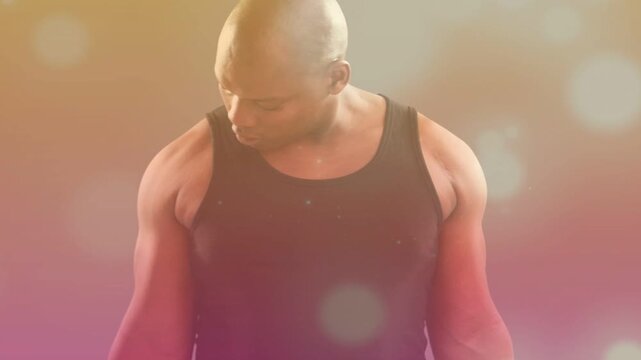 Gripping chrome dumbbells, fit man doing alternating biceps curls, checking form on warm gradient