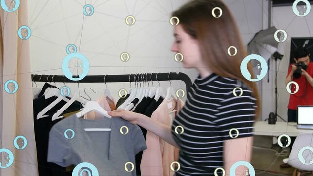 Stylist scanning rack pulling gray sweater checking for fashion shoot, icons floating over rack