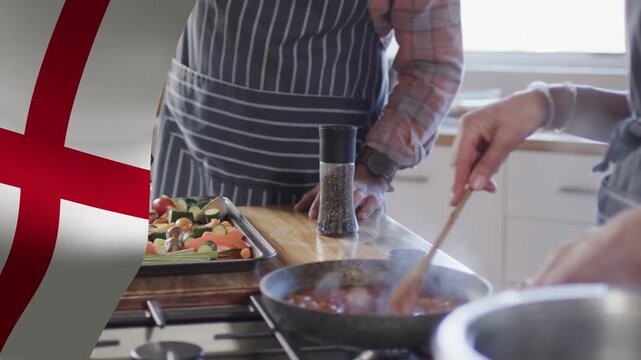 Right cook stirring cooking sauce with spoon, causing steam and flag graphic left cook prepping veg
