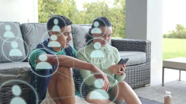 Couple sitting on porch woman reaching phone and causing icon overlay taking selfie for marketing