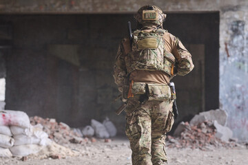 Obraz premium Military Soldier in Camouflage Gear Moving Through Abandoned Urban Building During Tactical Operation