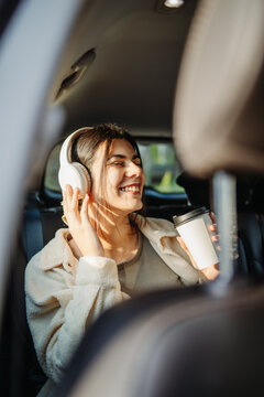Woman enjoying music in car drinking coffee