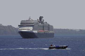 Luxury cruiseship cruise ship liner Eurodam anchoring at sea on sunny summer day during Mediterranean Greek Island Santorini caldera cruising with shore and rocky island in background © Tamme Wichmann