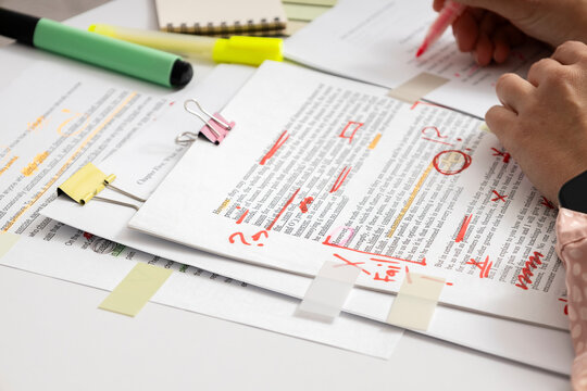Student or editor analyzing written assignment with notes and highlights, checking text for accuracy, clarity and academic quality