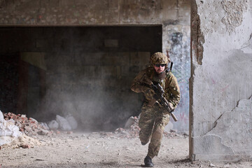 Obraz premium Soldier In Tactical Gear Running Through Abandoned Urban Building During Urban Combat Training Exercise