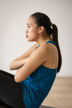 Tired and exhausted young Asian fitness woman in a gym after the crunch, abdominal muscle working out, panting and resting