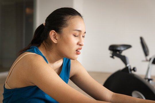Tired and exhausted young Asian fitness woman in a gym after the crunch, abdominal muscle working out, panting and resting