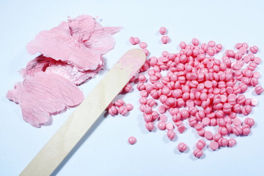 Pink Hard Wax Beans With Wooden Spatula And Used Wax Strips For Hair Removal On White Background