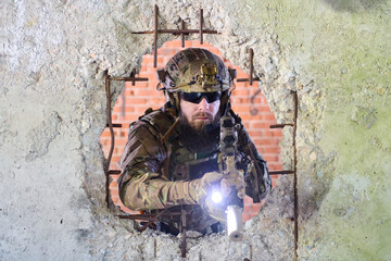 Obraz premium Tactical Soldier With Rifle Pointing Through Bullet-Hole Wall During Urban Combat Training