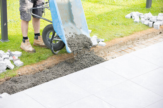 Construction worker pouring concrete from wheelbarrow for pavement installation