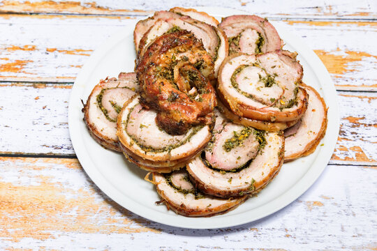 Well grilled porchetta sliced into rounds in a dish and ready to serve