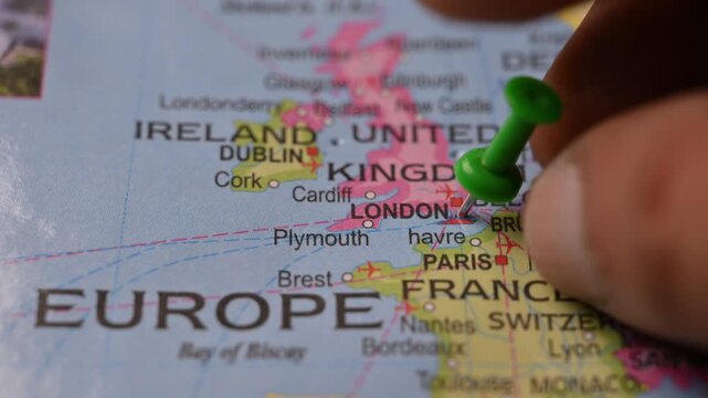 Close Up Man Pointing Green Pin on London United Kingdom Location on Paper World Map