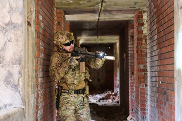 Obraz premium Tactical Soldier In Urban Combat Gear Clearing Abandoned Building With Rifle And Flashlight