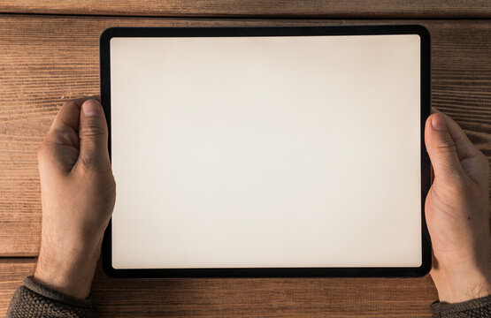 Close up of hands holding a tablet with a blank screen, perfect for mockups and presentations, over
