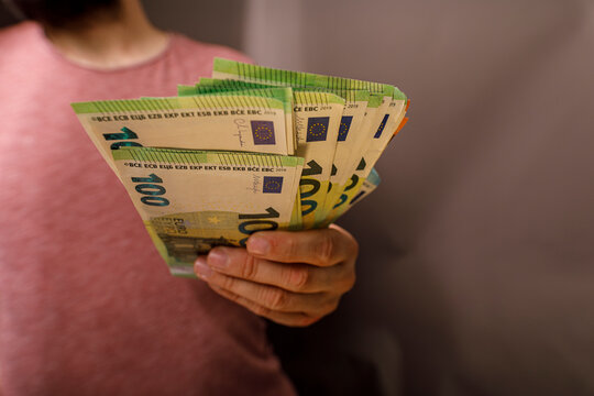 Close-up of a person holding Euro currency, representing savings, finance and making mone