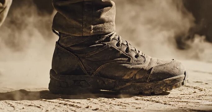 Close-up of a soldier walking through dry dust in rugged combat boots