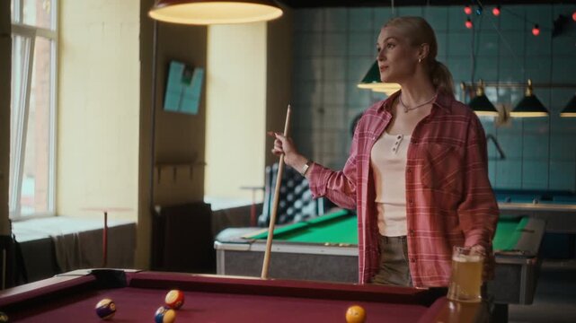 Over shoulder shot of young adult Black man shooting ball with cue on pool table while playing billiards with female friend over drinks at bar
