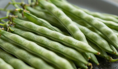 Fototapeta premium Fresh green beans piled on dark plate with blurred background