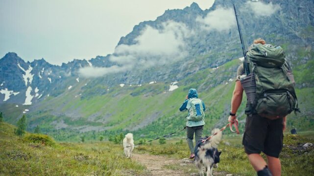 S&oslash;rTverrfjord, Loppa, Finnmark, Norway - Hikers Walk Their Dogs Along a Mountain Trail Beneath Misty Peaks and Patches of Snow - Static Shot