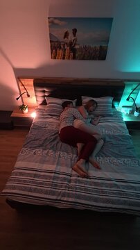 Top view of couple sleeping peacefully in modern bedroom with warm and cool night lighting both side vertical view.