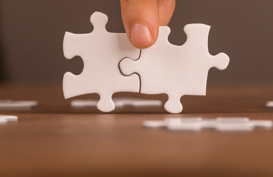 Hand fitting two puzzle pieces together. Teamwork, cooperation, solution, ideas and connection conce