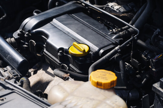 Car engine closeup background. Motor compartment detail. Vehicle maintenance concept scene. Yellow cap service image. Auto mechanics view. Transport technology part. Underhood repair system.