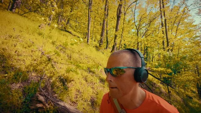A modern mature man in his 50s using wireless headphones and sunglasses while hiking. Intersection of technology, gadgets, and active outdoor lifestyle. 4k quality.