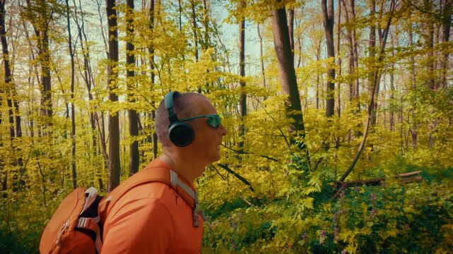 A modern mature man in his 50s using wireless headphones and sunglasses while hiking. Intersection of technology, gadgets, and active outdoor lifestyle. 4k quality.