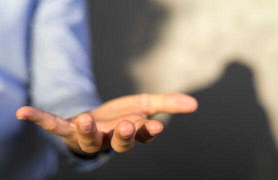Close-up of a hand reaching forward, suggesting offering, giving, support and connection.
