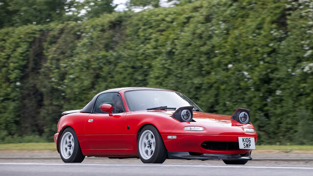Bicester,Oxon.,UK - Apr 26th 2026: 1992 red Mazda Eunos classic  car with pop up headlights driving on a British road