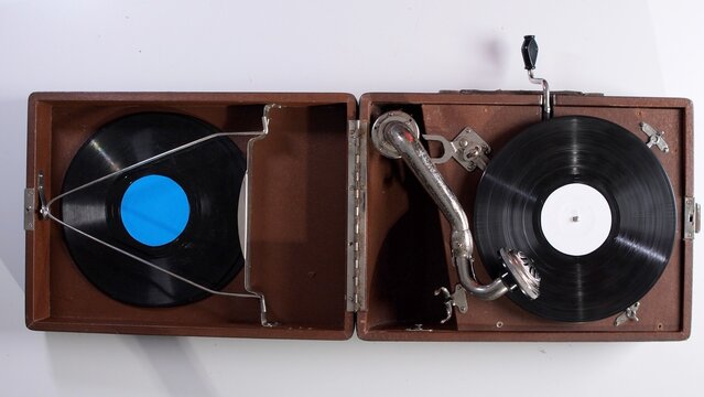 Portable wooden gramophone with a black shellac record spinning, showcasing a classic musical instrument designed for playing sound from antique media and bringing back retro memories