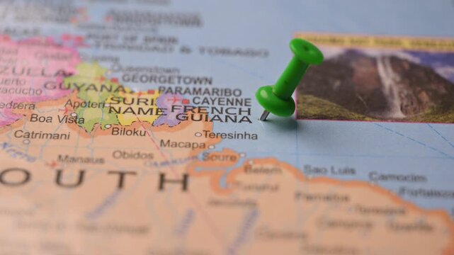 Hand Placing Green Pin on French Guiana Location in World Map for Travel Concept
