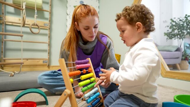 Female teacher teaching a toddler counting with abacus at daycare
