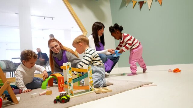 Toddlers and caregivers playing together in a modern daycare playroom