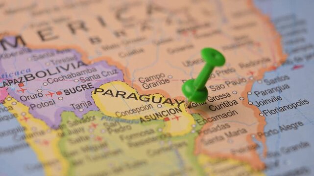 Hand Marking Paraguay with Green Pin on World Map for Travel Planning Concept Close Up